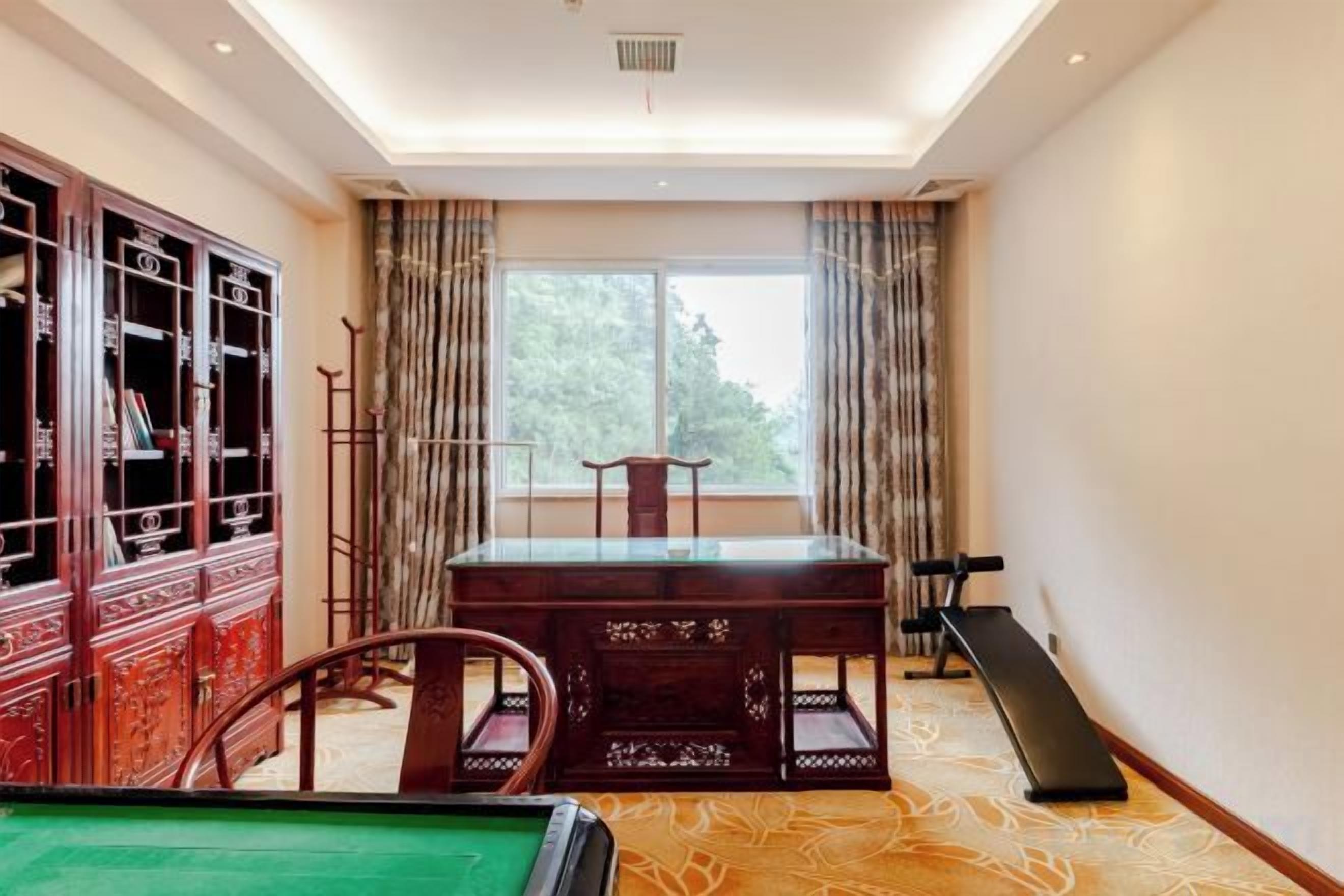 A billiards table, a wooden cabinet, and a window with curtains.
