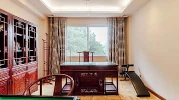 A billiards table, a wooden cabinet, and a window with curtains.