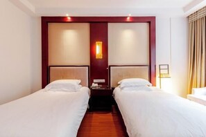 A hotel room with two single beds, a wooden floor, a red accent wall, and a nightstand with a lamp. - Zhongmei Hotel (Jinggangshan)