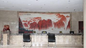 A reception area with a marble counter, two black chairs, and a large traditional painting on the wall.