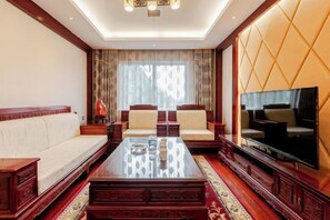 A spacious living room with a sofa set, a coffee table, and a television. - Zhongmei Hotel (Jinggangshan)