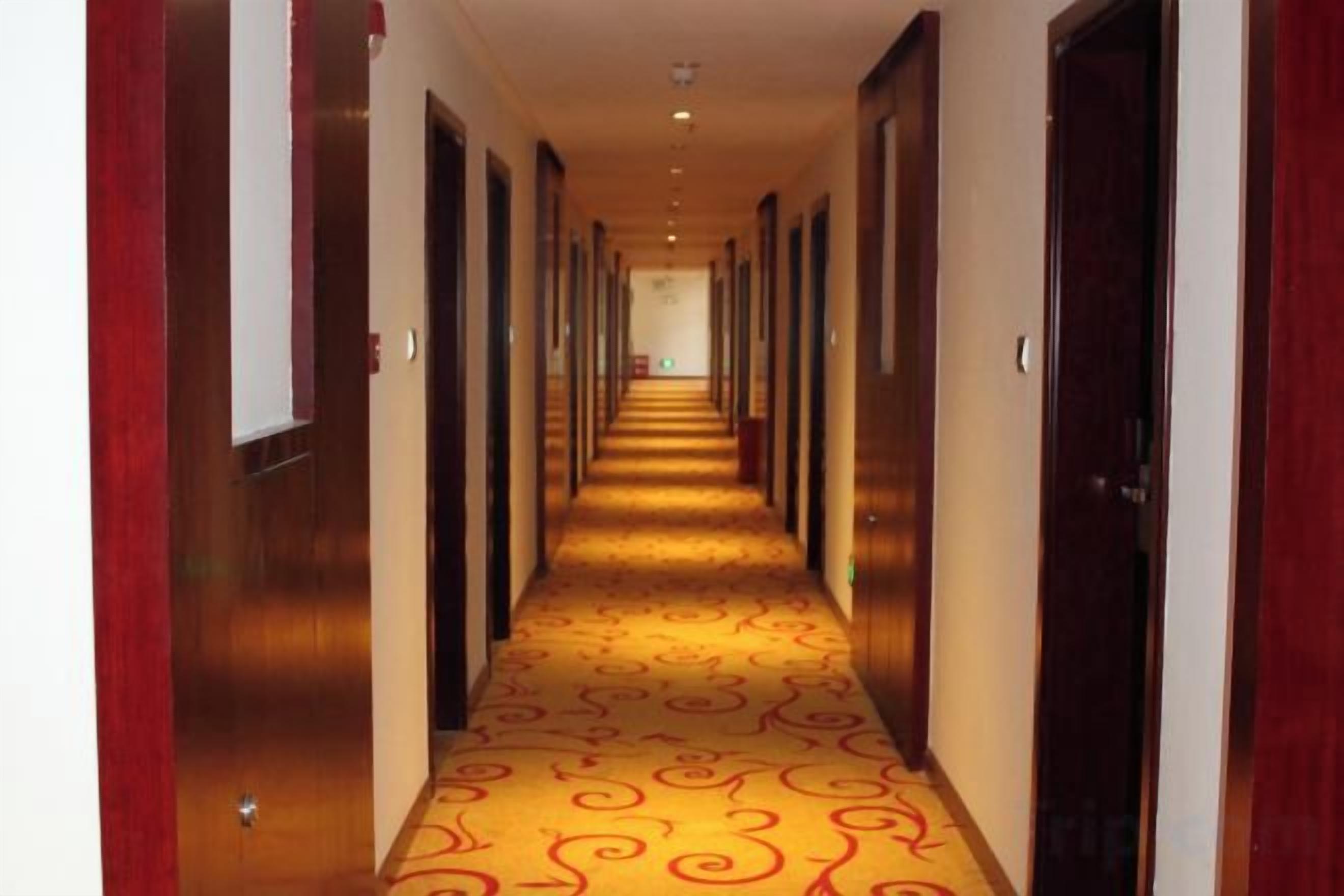 Un pasillo de hotel con alfombra estampada, puertas de madera y una larga extensión.