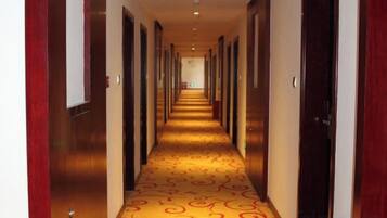 Un pasillo de hotel con alfombra estampada, puertas de madera y una larga extensión.