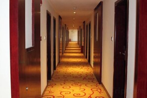 A hotel corridor with a patterned carpet, wooden doors, and a long hallway. - Zhongmei Hotel (Jinggangshan)