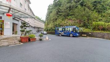 A building with a bus parked in front, surrounded by trees and a paved area.