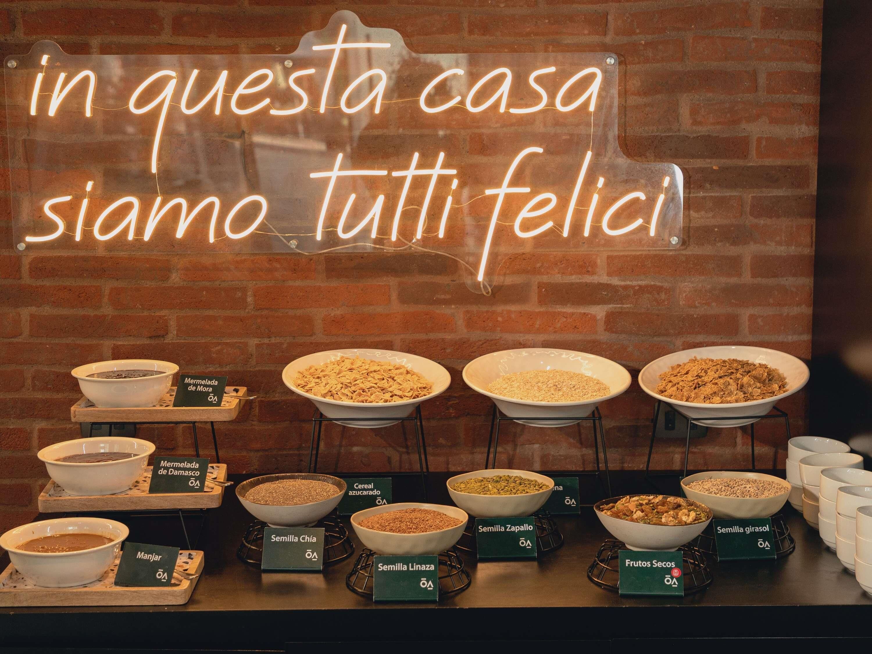 Um buffet de café da manhã com diversas tigelas de cereais e grãos, identificadas em espanhol.
