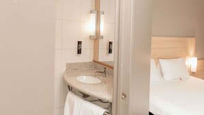 A hotel bathroom with a sink, mirror, and hand sanitizer dispensers. - ibis Santiago Las Condes (Santiago)