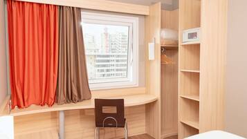 Una habitación con escritorio, silla y armario con estantes.