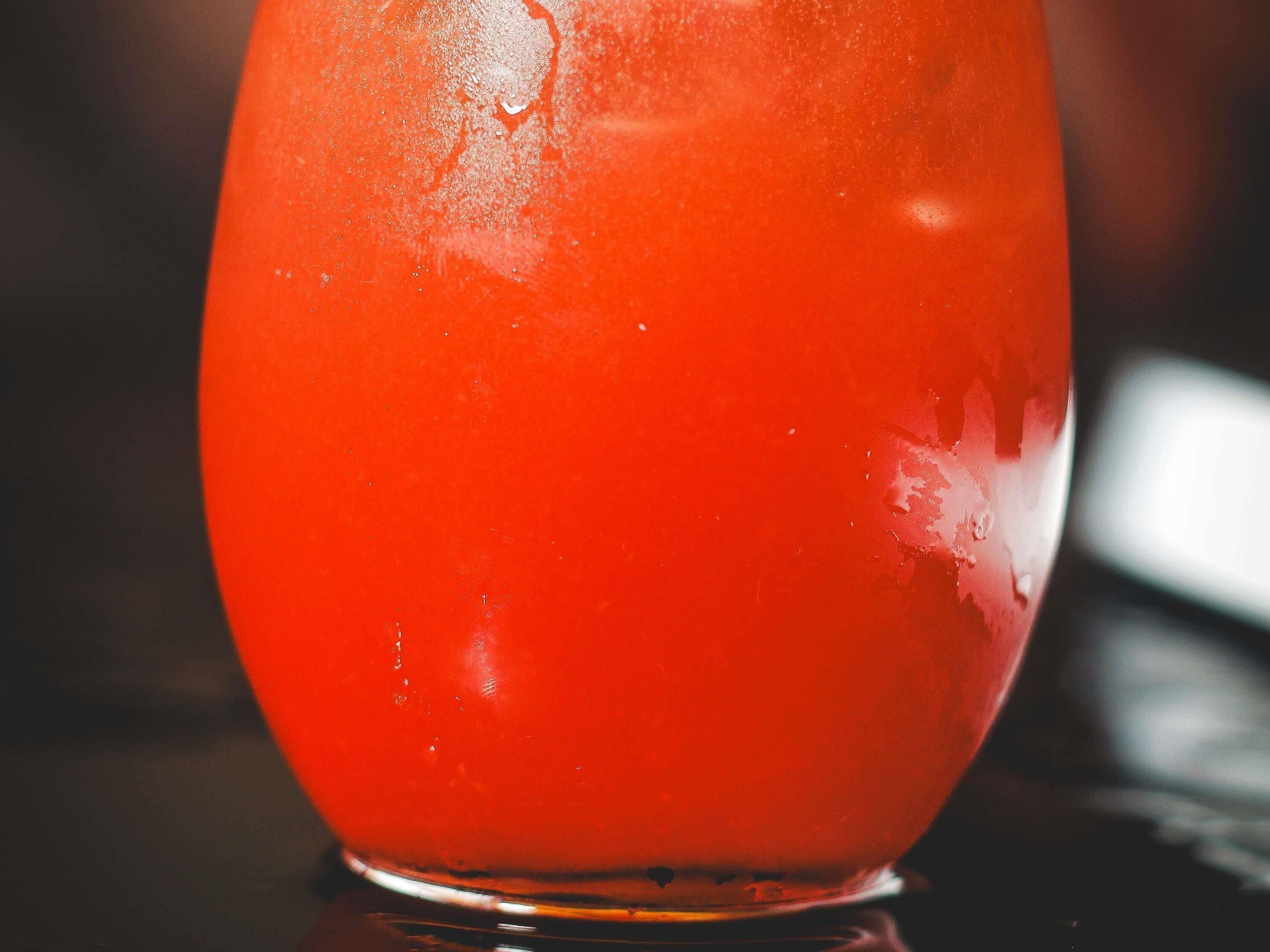 Gros plan d’un verre rouge sur lequel de la condensation s’est formée, et qui contient probablement une boisson.
