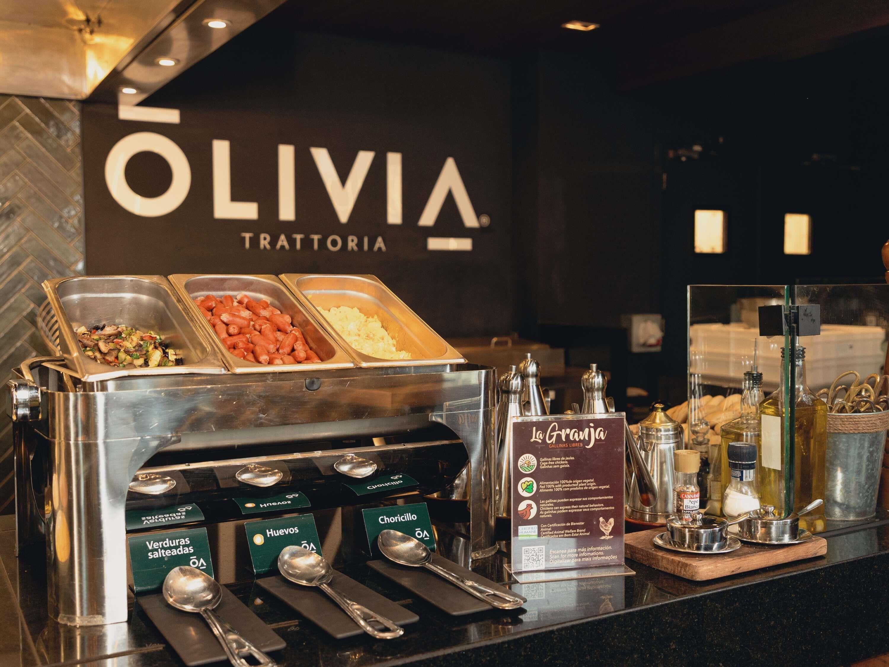 Ein Buffetbereich mit beschrifteten Speisebehältern, einer Kaffeemaschine und einem Schild für 'La Granja' mit einem QR-Code.
