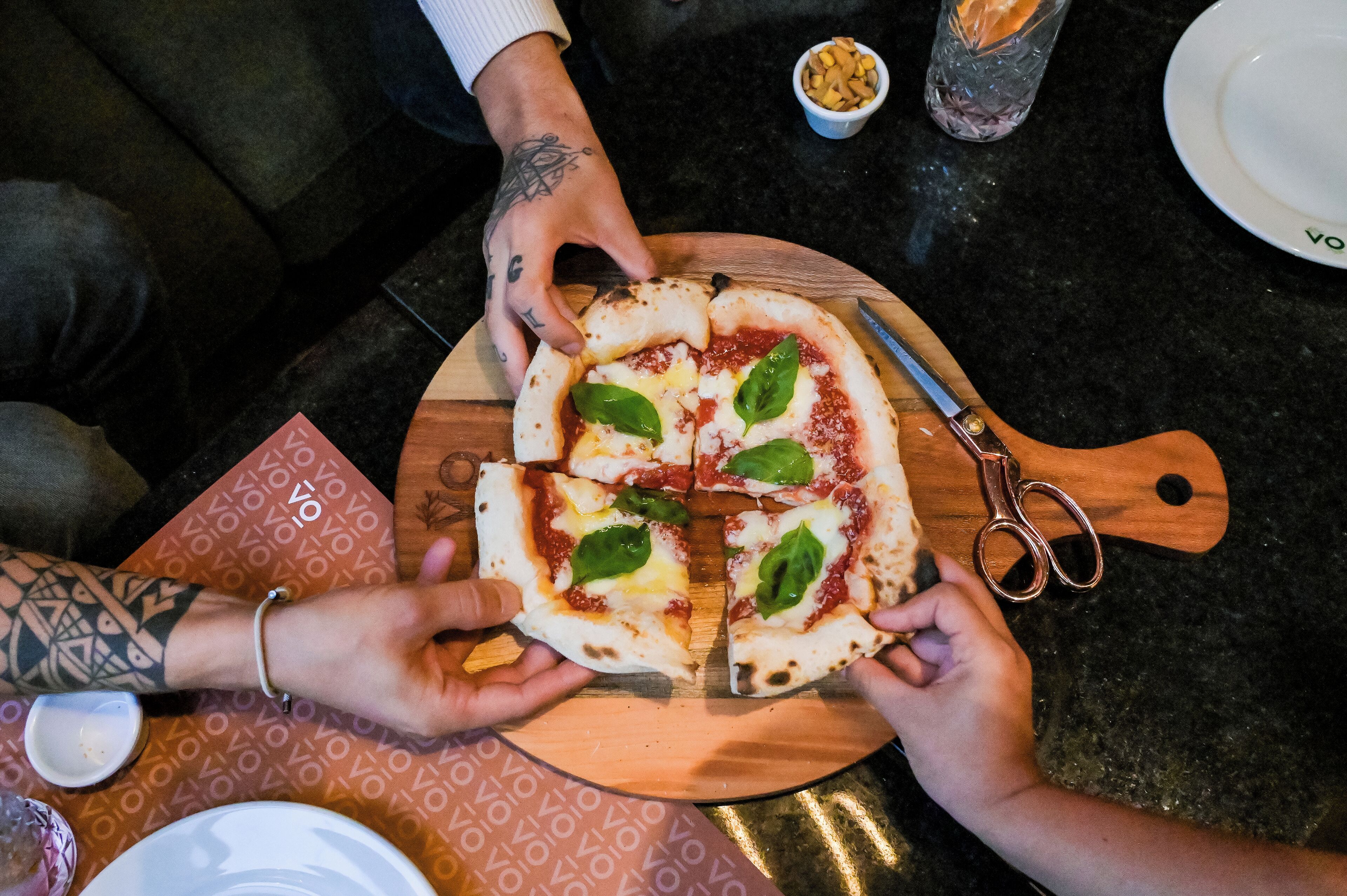 A pizza being cut into slices on a wooden board.