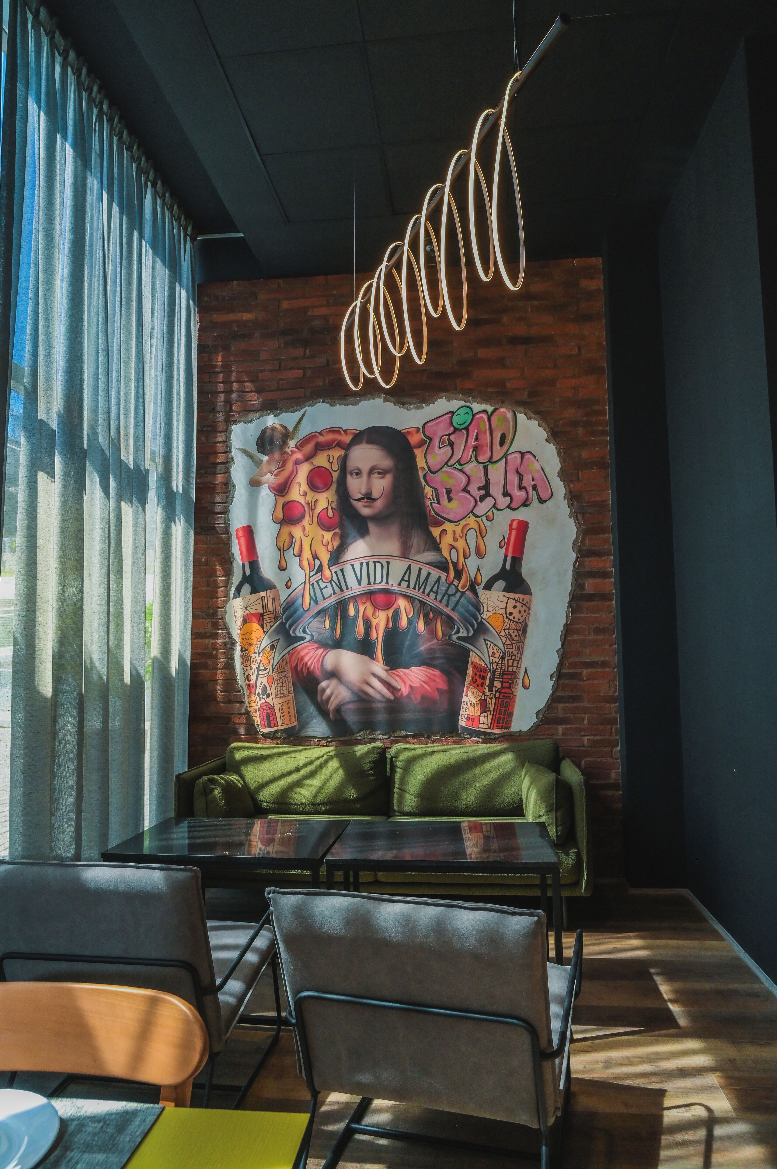Un comedor con un mural, una lámpara colgante y vistas por una ventana.