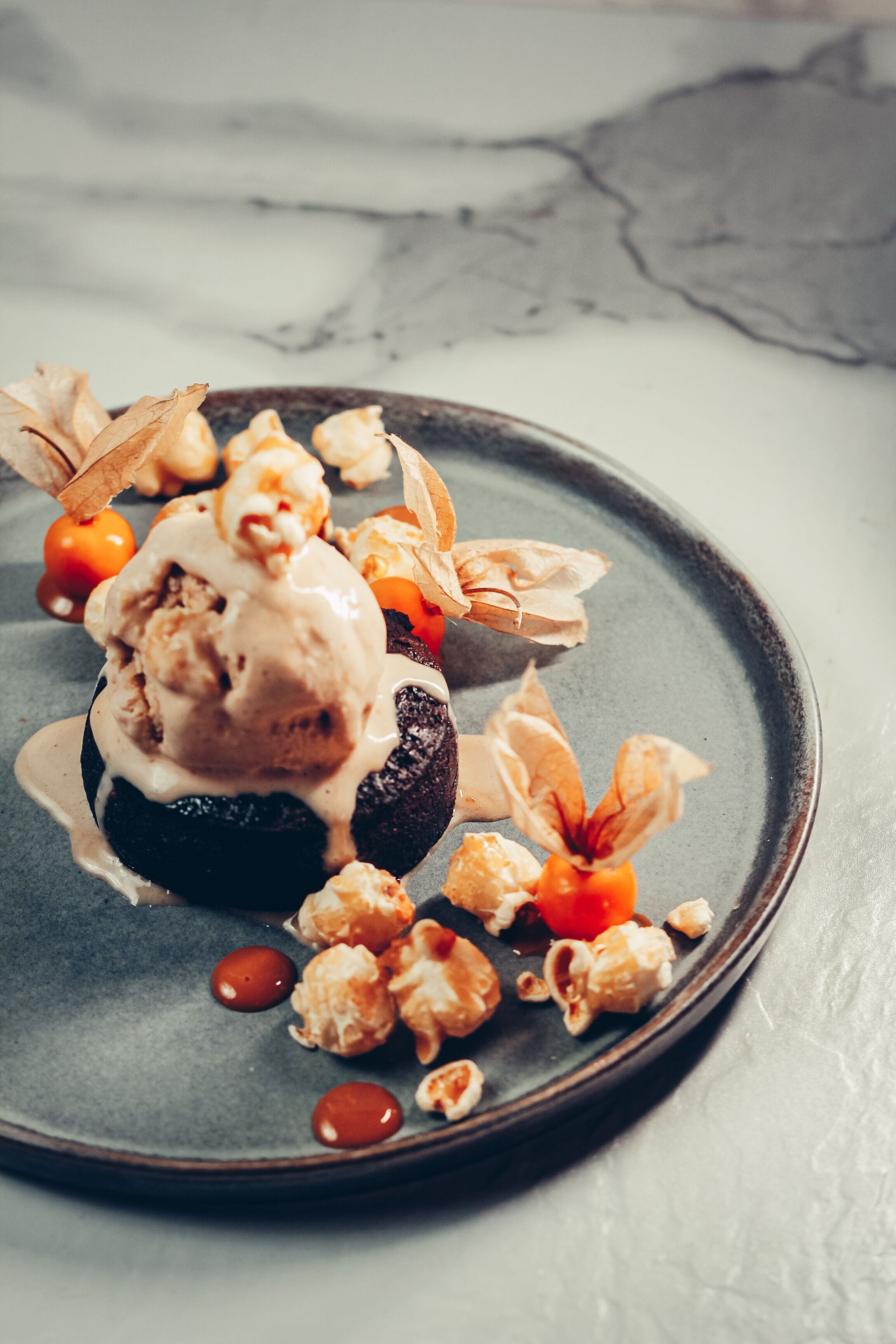 A dessert on a plate with caramel and a scoop of ice cream on top.