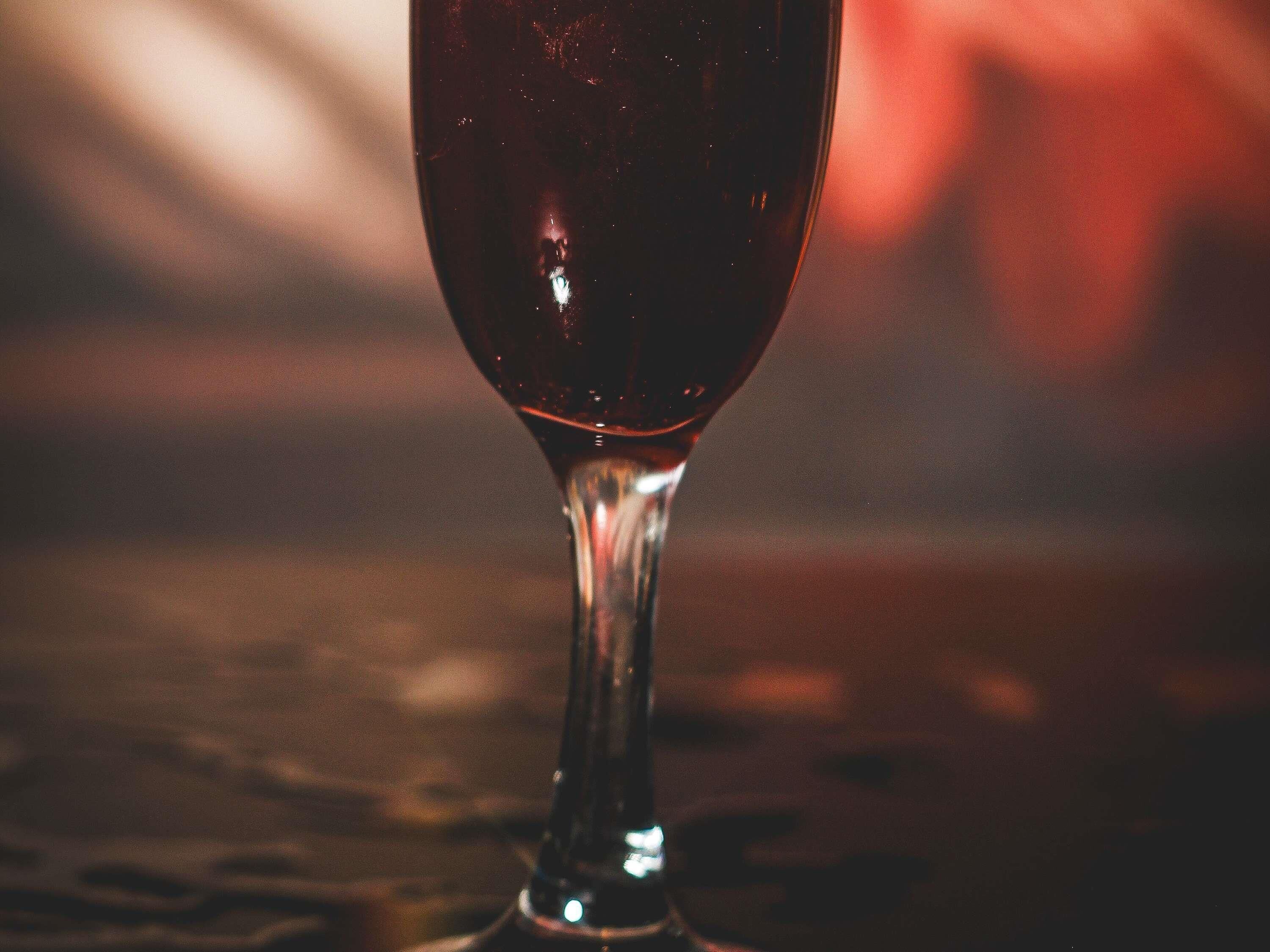 Primer plano de una copa de vino sobre una superficie reflectante.