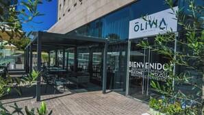 A modern building with a glass facade and outdoor seating area. - ibis Santiago Las Condes (Santiago)