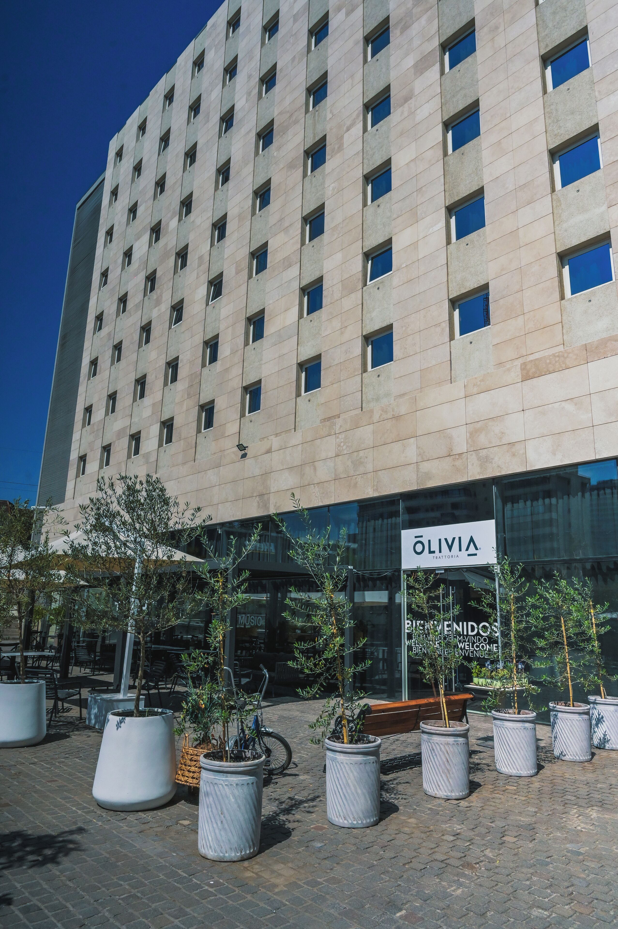 A modern building with a sign reading "OLIVIA" and "BIENVENIDOS" welcoming visitors.