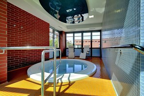 A modern indoor swimming pool with a glass wall, a brick wall, and a tiled floor. - St. Joseph ROYAL REGENT (Karlovy Vary)