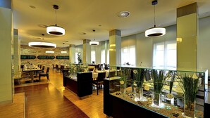 A modern restaurant with wooden flooring, glass partitions, and pendant lighting.