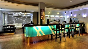 A modern bar area with a bar counter, seating, and a display of bottles.
