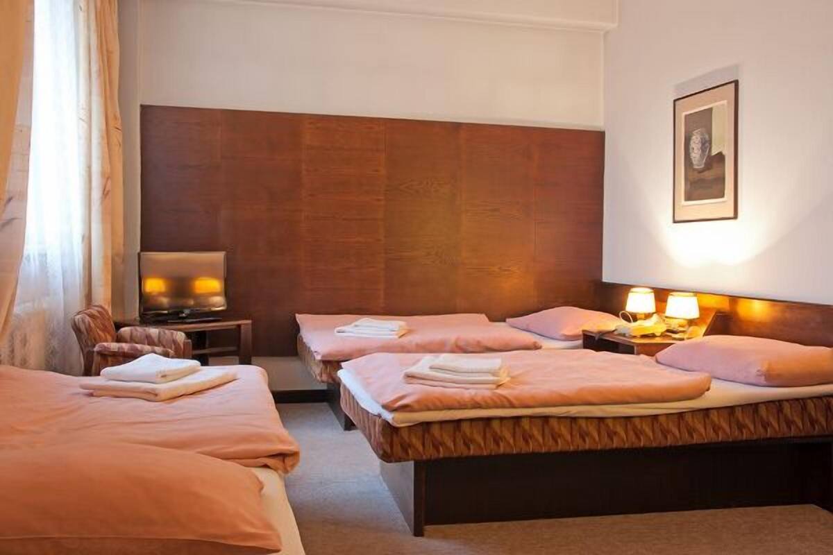 A hotel room with two beds, a TV, a desk, and a framed picture on the wall.