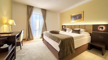 Ein Hotelzimmer mit Bett, Schreibtisch, Stuhl, Lampe und einem Bild an der Wand.