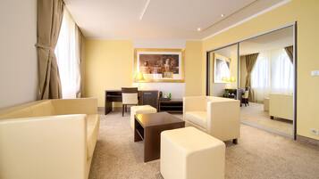 Habitación de hotel con sofá, sillón, mesa de centro, escritorio, lámpara y un espejo grande.