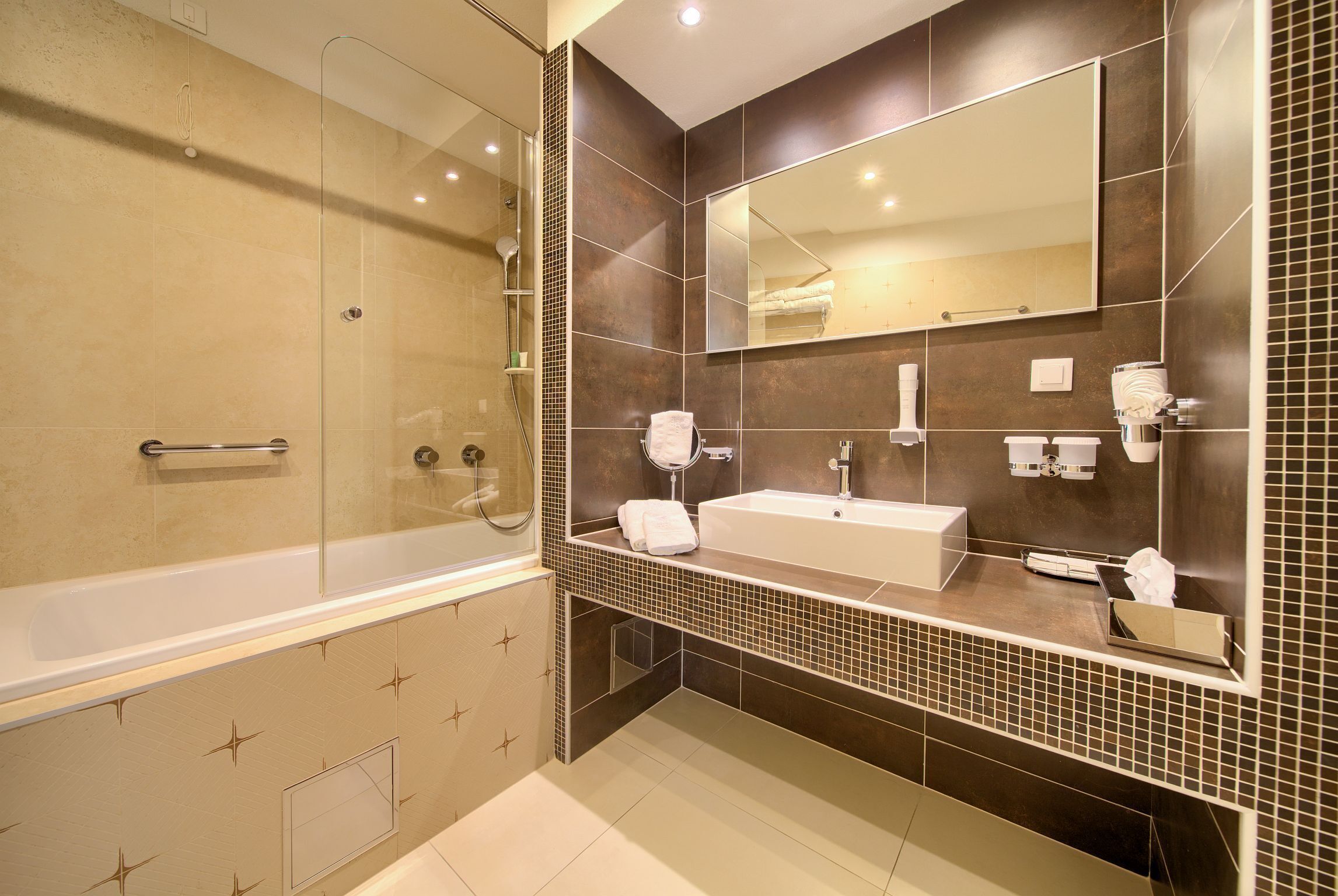 A modern bathroom with a bathtub, sink, and large mirror.