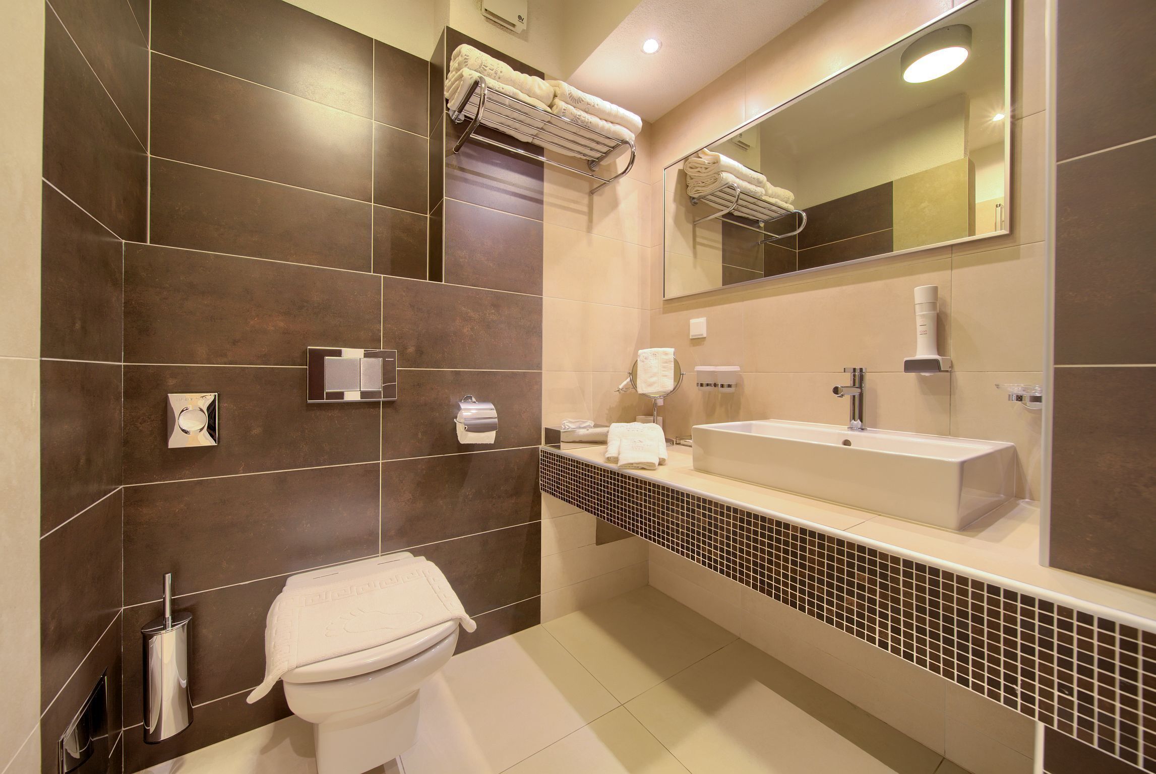 Un baño moderno con inodoro, lavamanos, toallero y espejo.