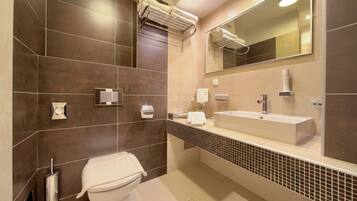 Un baño moderno con inodoro, lavamanos, toallero y espejo.