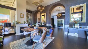 A spacious living area with a fireplace, dining table, and chairs, a kitchen area with a refrigerator, and a large mirror reflecting the room.