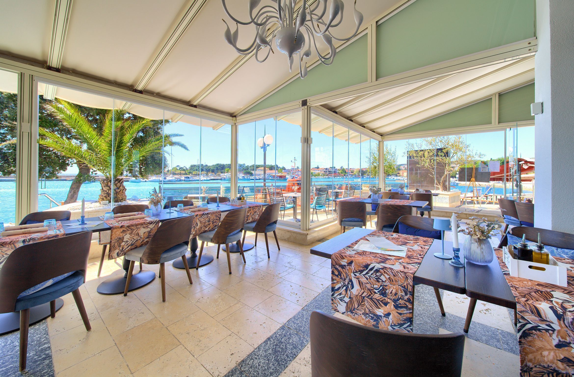 An indoor dining area with tables, chairs, and a view of the sea.