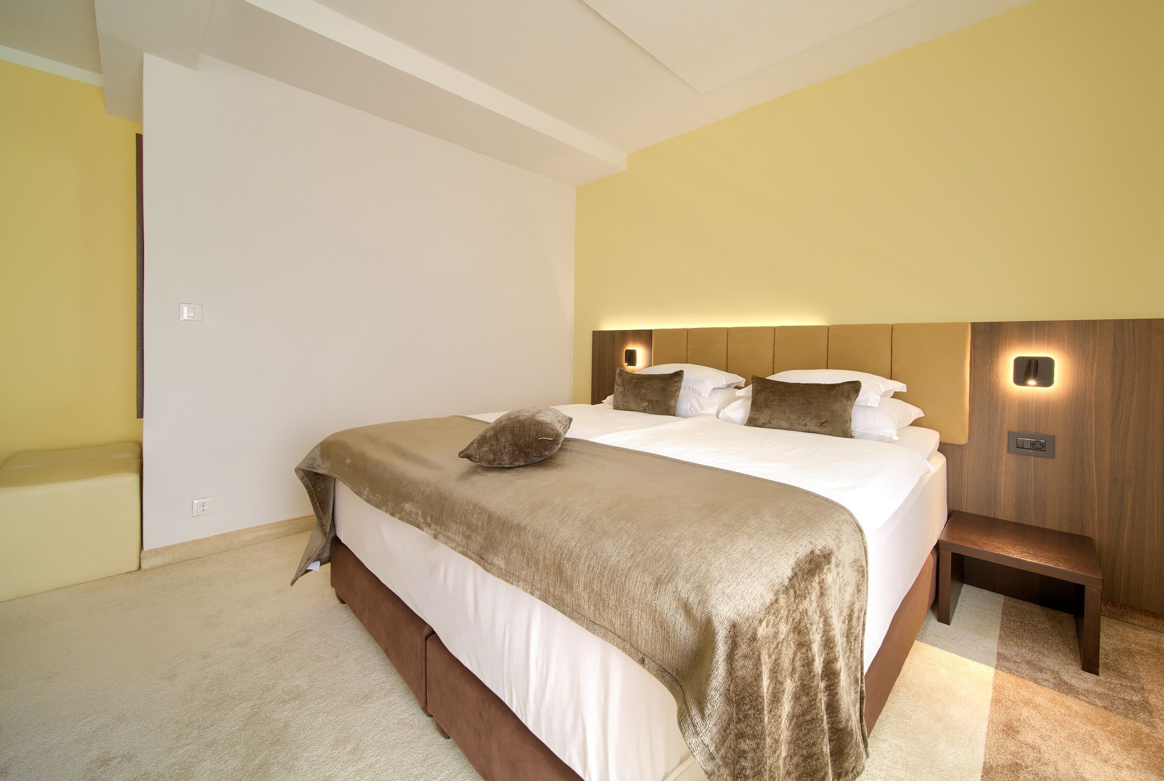Un dormitorio con una cama grande, mesitas de noche y un banco.
