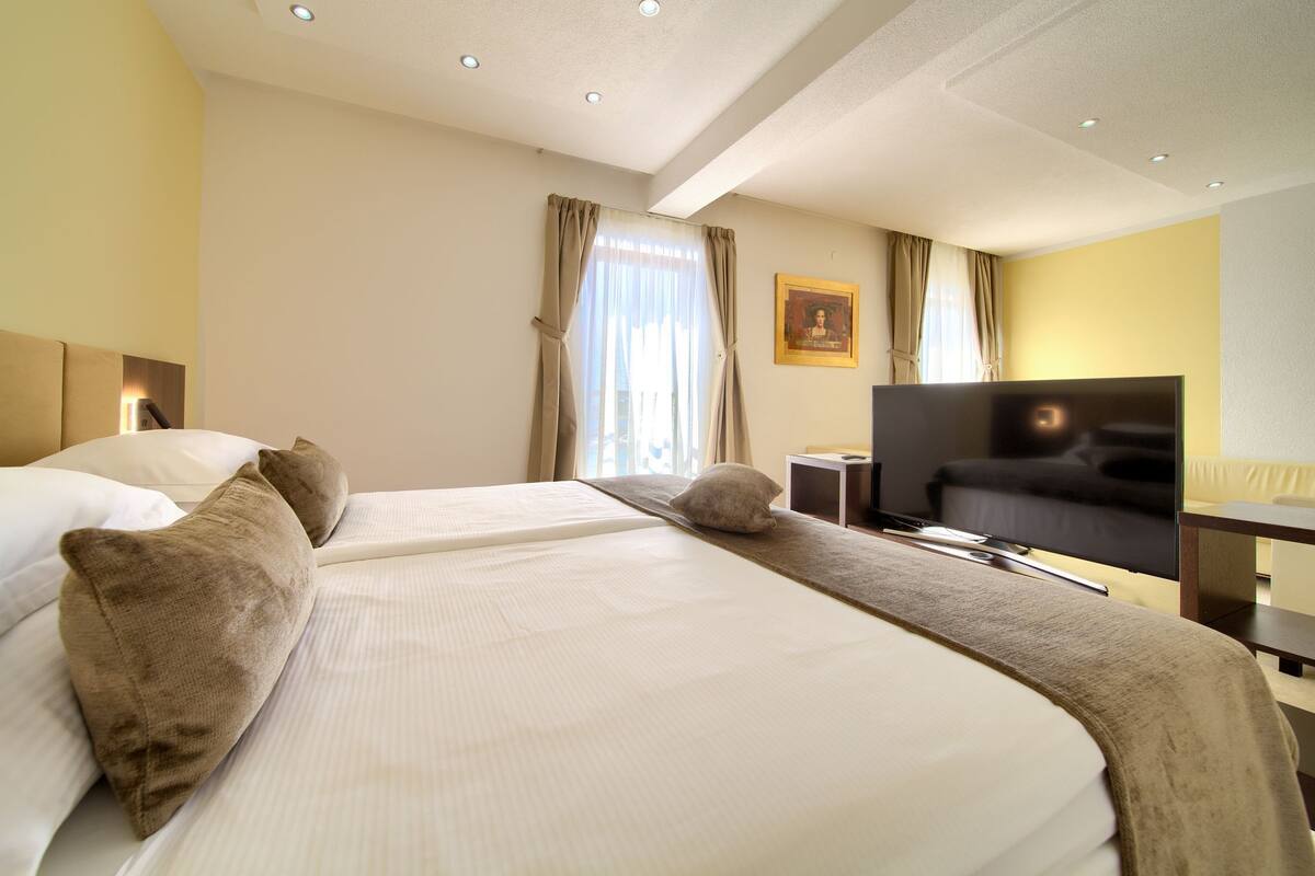 Een hotelkamer met twee bedden, een flatscreen-tv, een bureau en een stoel.