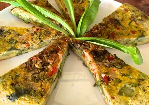 A plate of food with a slice cut out, surrounded by green leaves.