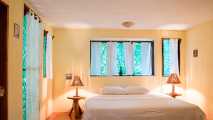 A bedroom with a large bed, two bedside tables with lamps, a window with curtains, and a door. - Nosara B&B Retreat (Nosara)
