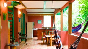 A room with a hammock, a dining table, chairs, and a kitchen area. - Nosara B&B Retreat (Nosara)
