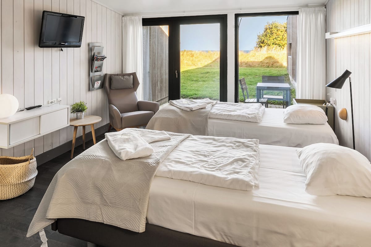 Une chambre d’hôtel avec deux lits, une télévision, un bureau avec une lampe et une vue sur l’extérieur.