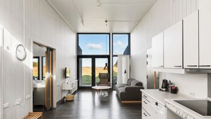 A modern kitchen with a dishwasher, a dining area with a round table, and a sofa. - Musholm Ferie-Sport-Konference (Korsor)