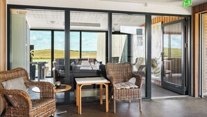A modern interior with wicker furniture, a glass door leading to a balcony, and a view of the outdoors. - Musholm Ferie-Sport-Konference (Korsor)