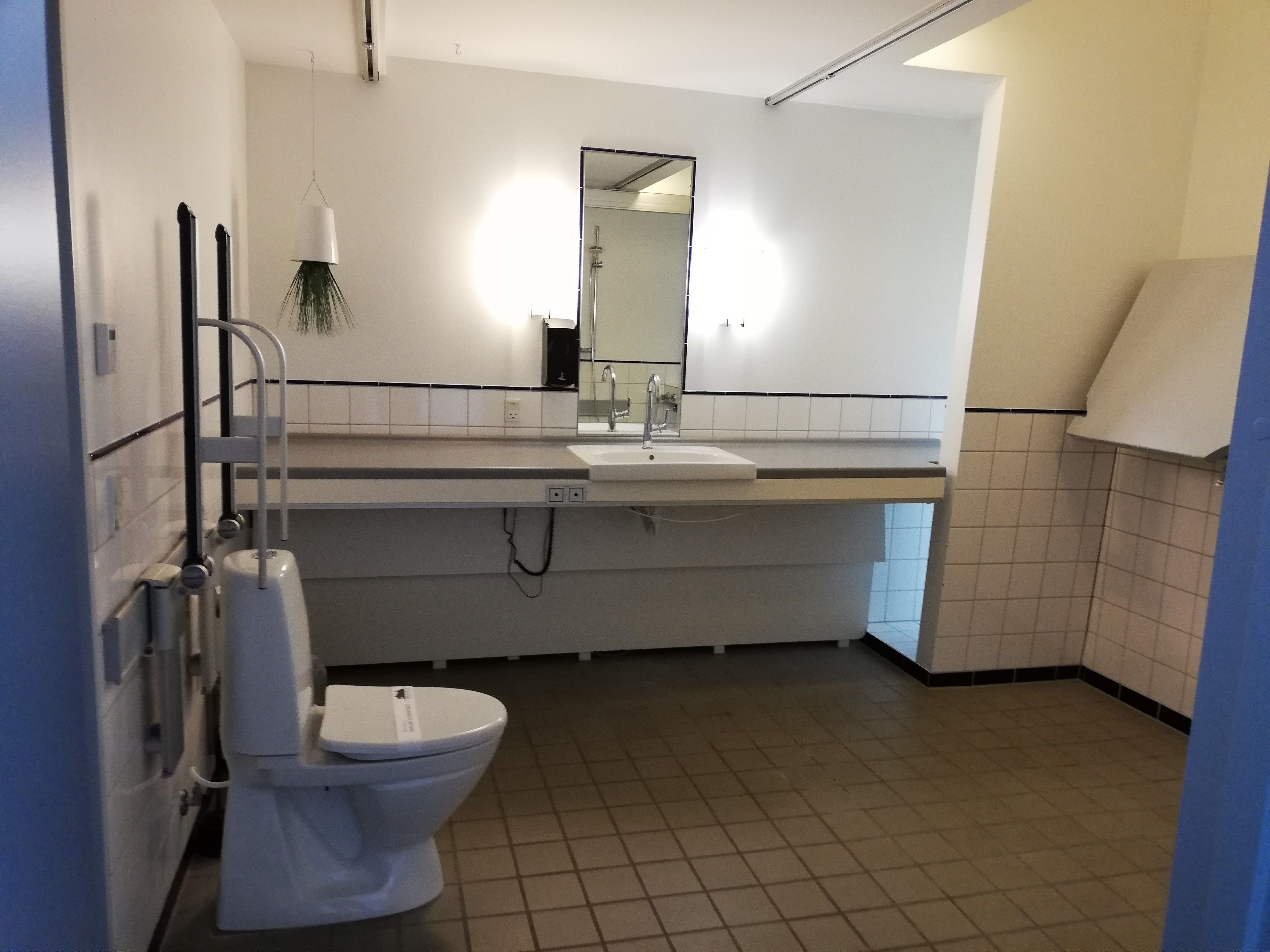 Une salle de bain moderne avec des toilettes blanches, un lavabo et un miroir au-dessus.