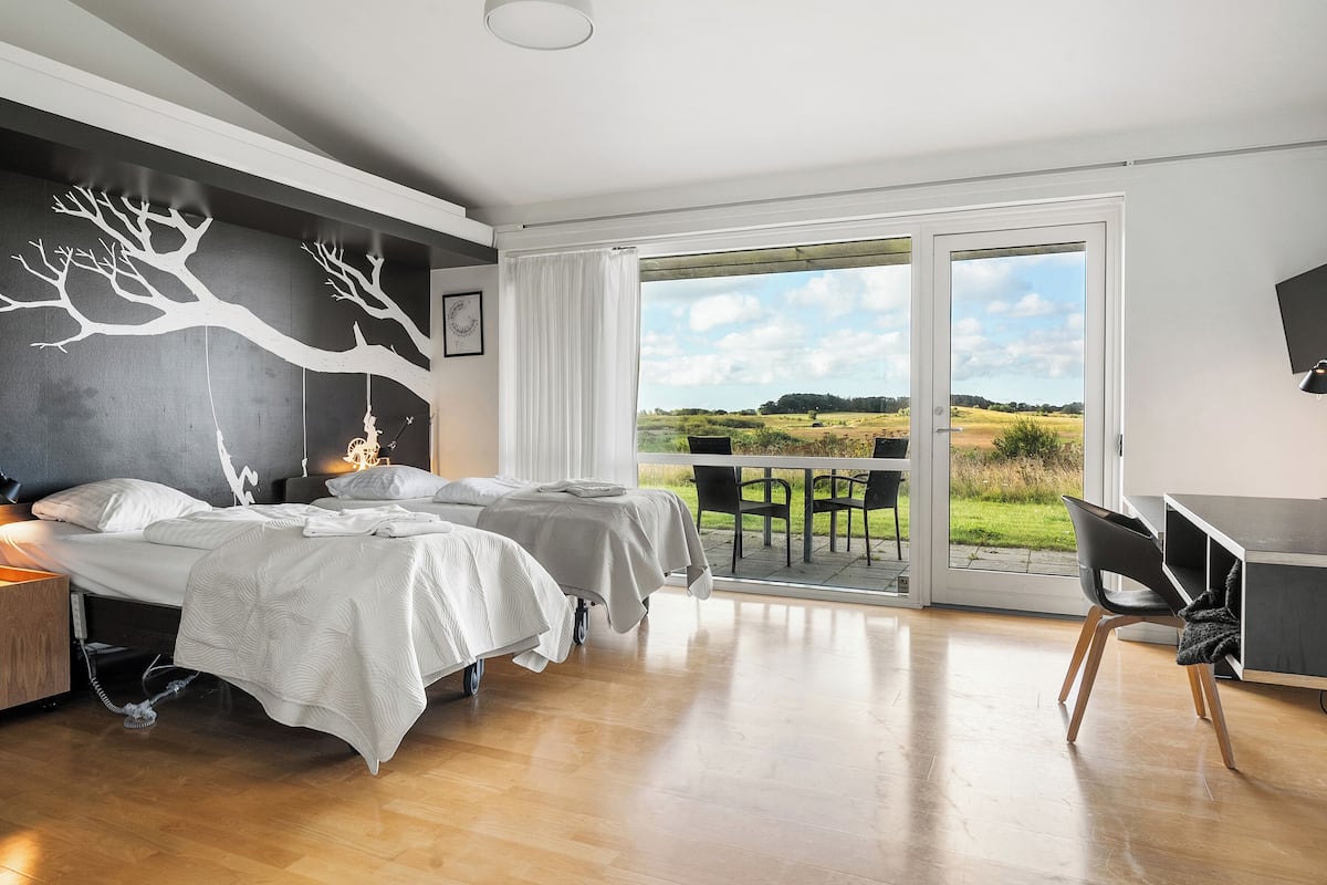 Une chambre avec deux lits, un bureau et une vue sur l’extérieur.