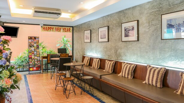 A hotel lobby with a seating area, a 'Happy New Year' banner, framed pictures on the wall, and a TV screen. - Sunshine House (Chiang Mai)