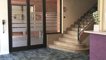 Un vestíbulo de hotel con una escalera, una recepción y una silla roja.