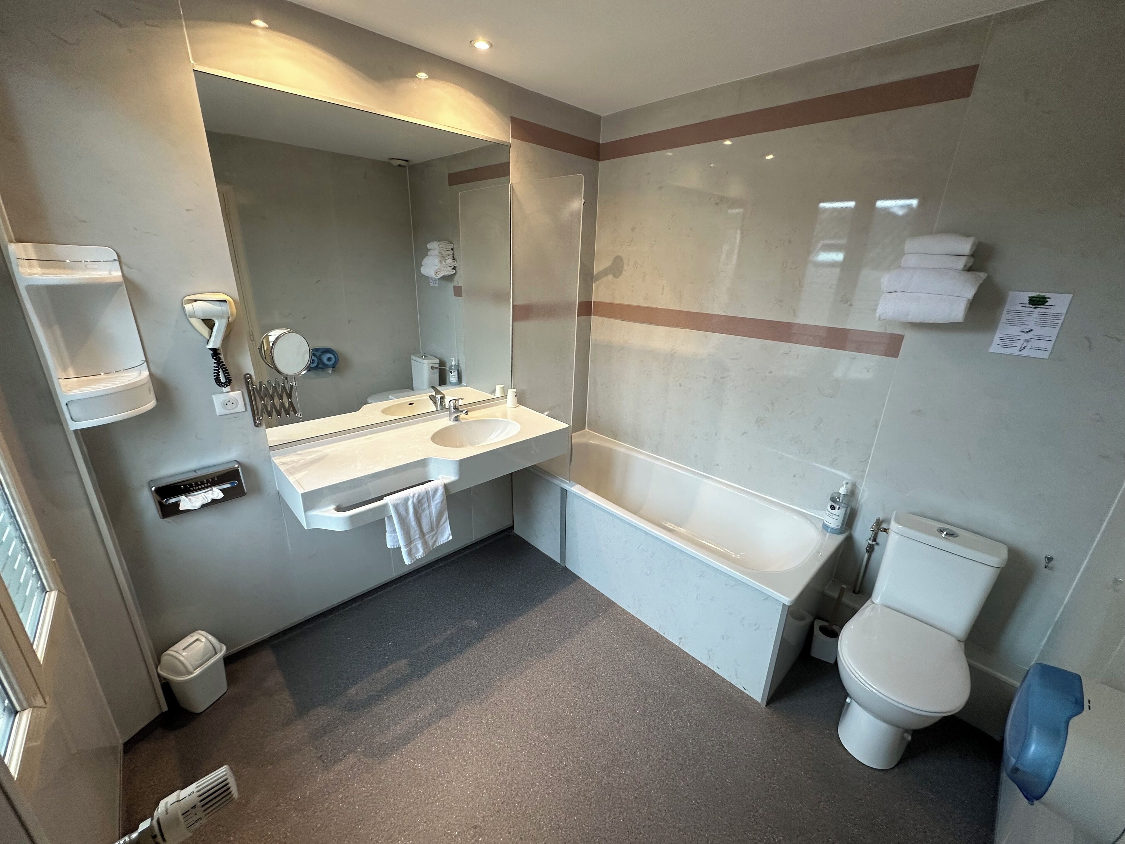 A modern bathroom with a dual sink vanity, a large mirror, a toilet, and a shower area.