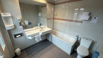 A modern bathroom with a dual sink vanity, a large mirror, a toilet, and a shower area.