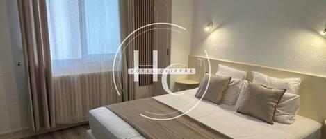 Une chambre d’hôtel avec un lit, des rideaux, une table de chevet et une lampe fixée au mur.