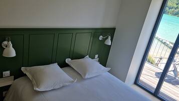 A bed with white bedding and pillows, a green headboard, and two wall-mounted lamps.