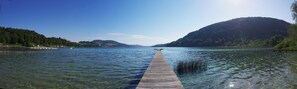 A wooden pier extending into a calm lake surrounded by forested hills.