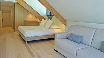 Un dormitorio con cama, sofá, vigas de madera y una ventana.