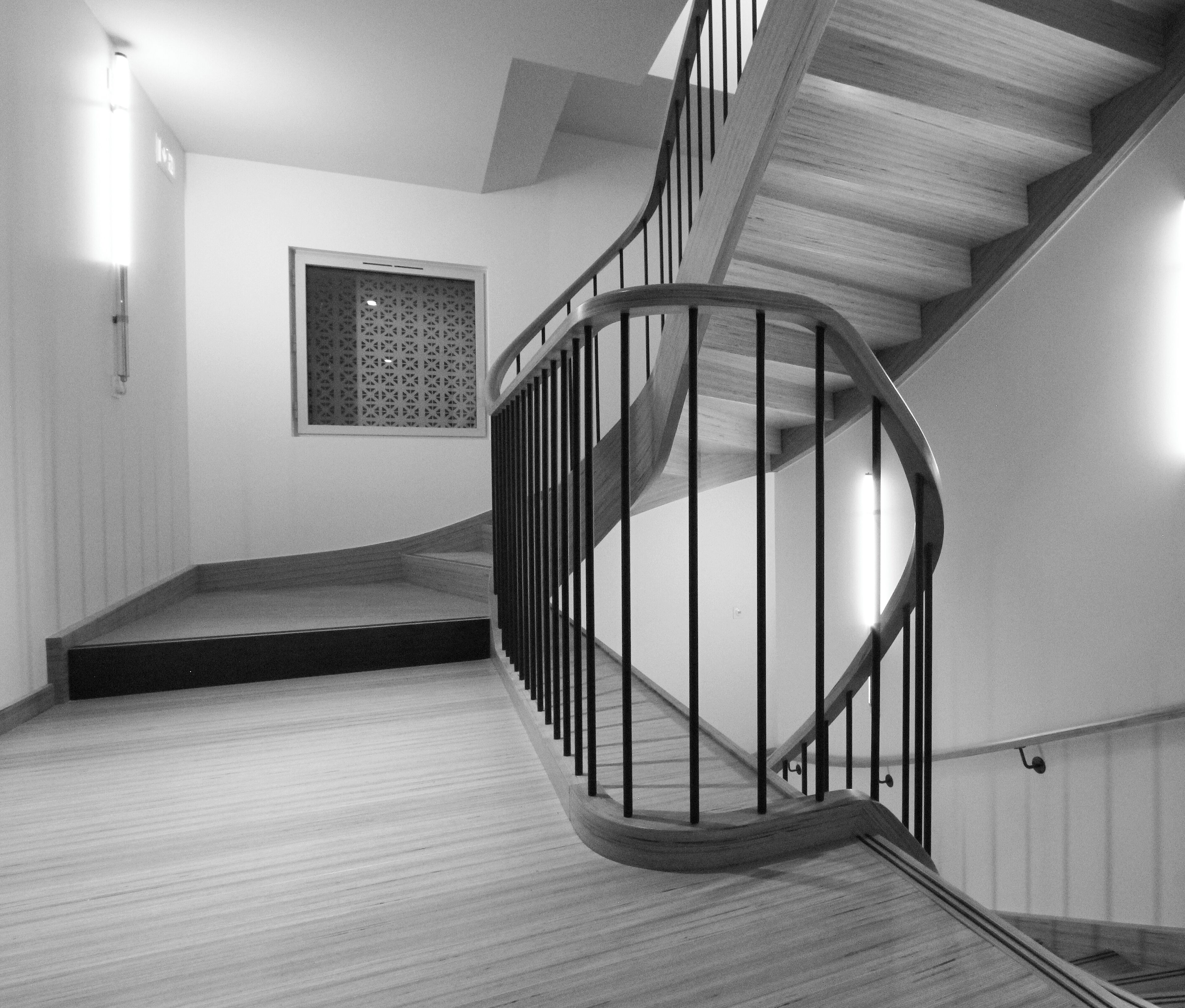 A spiral staircase with a wooden finish and black metal railings, leading to an upper floor.